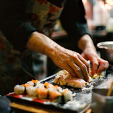 Fototapeta  - main d'un chef qui prépare des sushis