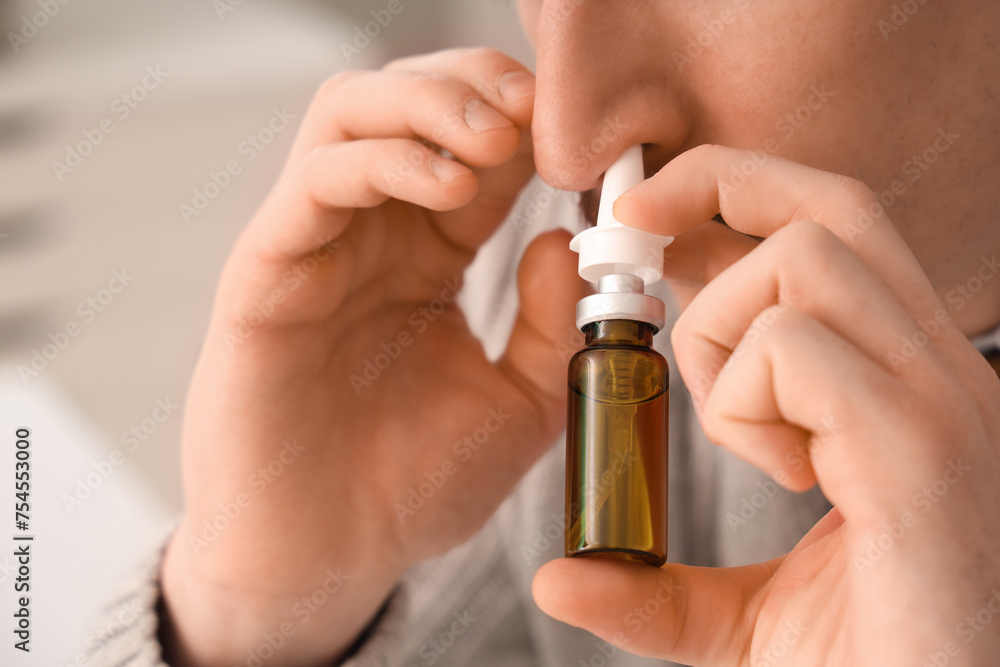 Ill businessman using nasal drops in office, closeup