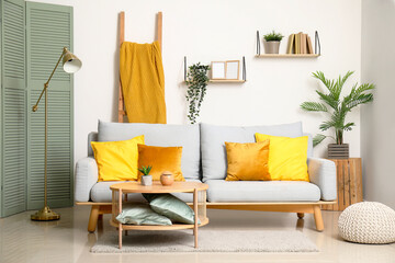 Sticker - Stylish interior of living room with soft sofa, pillows, houseplant and table