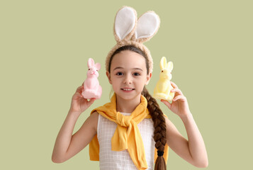 Poster - Cute little girl with bunny ears and toy rabbits on green background. Easter celebration