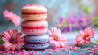 Pile of macaroons of pastel colors and colorful flowers against a bright floral background with copy space on the right