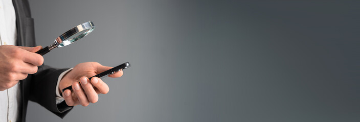 Wall Mural - A man looks at a phone with a magnifying glass