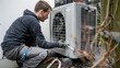 © Fokke Baarssen - worker installing an air source heat pump unit outdoors at a house in Europe, warmte pomp, translation air source heat pump, airco for warming and cooling,