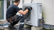 © Fokke Baarssen - male Engineer worker installing an air source heat pump unit outdoors at a house in Europe, warmte pomp, translation air source heat pump, airco for warming and cooling,