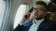Successful and handsome businessman in suit talking on cell phone sitting on plane during business trip