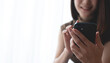 © tippapatt - Happy young asian woman checking social media on mobile phone at home. Smiling young woman sitting on sofa using smartphone app for online shopping and mobile banking. people lifestyles
