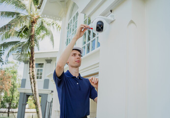 Wall Mural - A technician installs a CCTV camera on the facade of a residential building.