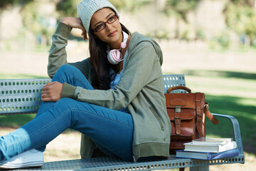 Wall Mural - Thinking, relax and student in park with books for studying, learning and reading outdoors. Education, happy and person with bag, textbooks and headphones on bench for university, campus or college