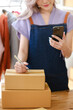 © Treerat - Online shopping concept, Female entrepreneur talks on smartphone and writes address on parcel boxes.