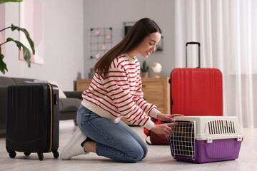 Sticker - Smiling woman preparing to travel with dog indoors. Suitcases and pet carrier around her