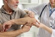 © New Africa - Arthritis symptoms. Doctor examining patient's elbow in hospital