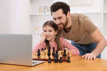 Poster - Father teaching his daughter to play chess following online lesson at home