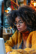 © ebhanu - A young African American hipster woman with Afro hair  sitting at a cafe table.