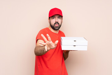 Wall Mural - Young man holding a pizza over isolated background nervous stretching hands to the front