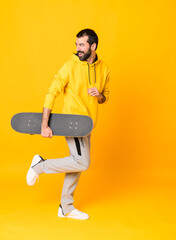Wall Mural - Full-length shot of a skater man over isolated yellow background