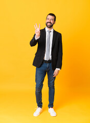 Wall Mural - Full-length shot of business man over isolated yellow background happy and counting three with fingers
