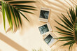 top view of wooden frames with tropical palm leaves on beige background