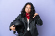 Young asian woman with a motorcycle helmet isolated on purple background showing thumb down with negative expression