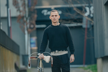 Wall Mural - young man with bicycle walking on the street