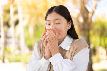 Wall Mural - Pretty Chinese woman at outdoors holding an orange