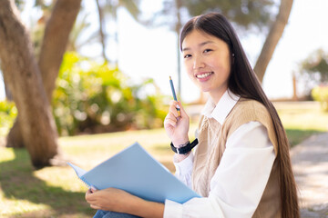 Wall Mural - Pretty Chinese woman at outdoors holding a notebook