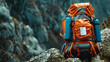 An orange backpack with blue sleeping pad attached rests on natural rocky ground surrounded by foliage