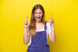 Young caucasian woman isolated on yellow background with fingers crossing