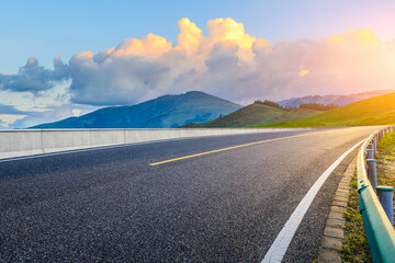 Asphalt highway road and green mountain nature landscape at sunset