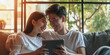 A happy young Asian couple is watching a movie online on a tablet. Close-up, bokeh in the background.