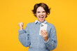 © ViDi Studio - Young overjoyed woman she wears grey knitted sweater shirt casual clothes hold in hand use mobile cell phone do winner gesture isolated on plain yellow background studio portrait. Lifestyle concept.
