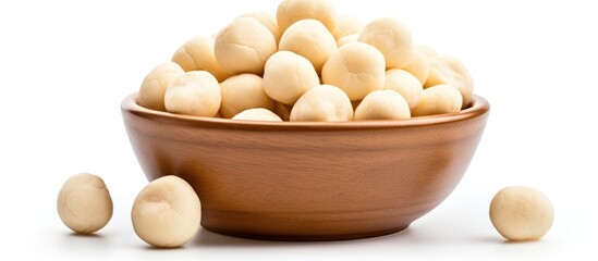 Wall Mural - A mixing bowl filled with macadamia nuts, a delicious ingredient often used in recipes from various cuisines, placed on a white tableware background