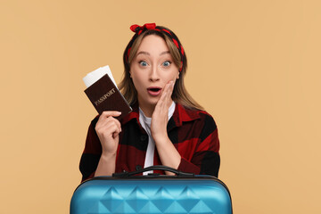 Wall Mural - Emotional young woman with passport, ticket and suitcase on beige background