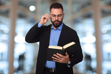 Poster - Confident lawyer in glasses reading book on blurred background