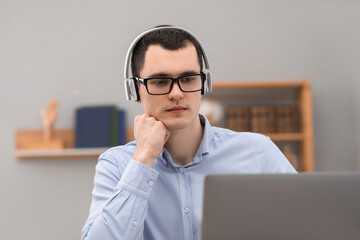 Wall Mural - E-learning. Young man using laptop during online lesson indoors