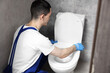 © New Africa - Plumber wearing protective gloves repairing toilet bowl in water closet