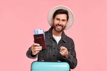 Poster - Smiling man pointing at passport and tickets on pink background