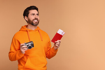 Poster - Smiling man with passport, camera and tickets on beige background. Space for text