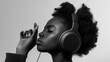 Black and white portrait of a young black woman in headphones with her eyes closed. Concept of audio product advertisement, relaxation, wellness promotion