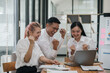 © amnaj - Three ecstatic asian business professionals celebrating a victory with a fist pump in a modern office.
