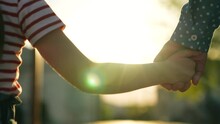 Happy Family Mother And Daughter Holding Hands Walking Together At Bright Sun Light Summer Park Closeup. Little Baby Kid Child And Female Parent Arm Enjoy Outdoor Weekend Activity With Love Tenderness