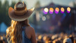 Young American woman fan of country music attending a country music concert. Back view of a woman wearing a cowboy hat and copy space for text or logo.	