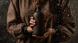 Dynamic image of hands gripping a coffee-filled bottle amidst a creative spray of coffee drops, ideal for branding and promotions