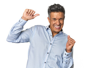 Middle-aged Latino man celebrating a special day, jumps and raise arms with energy.