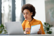 © Prostock-studio - Focused young black woman studying with laptop and notebook