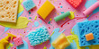 Top view of colorful cleaning sponges and brushes amidst playful paint splashes on a vivid background