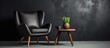 © Lasvu - A cosy armchair and a minimalistic coffee table are placed against a black wall. On the table, there is a potted plant, creating a simple and elegant interior design.