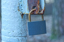 One Closed Iron Rusty  Industrial Modern Gray Padlock Hanging On A Rusty Bracket During The Day On The Street