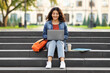 © Prostock-studio - Smiling indian student woman sitting on stairs working on laptop