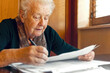 © ADDICTIVE STOCK - A senior lady concentrates intently on filling out documents at her table. Generative AI