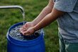 © Halfpoint - Boy washing his hands with water from a well. Well with a pump for outdoor washing in garden.